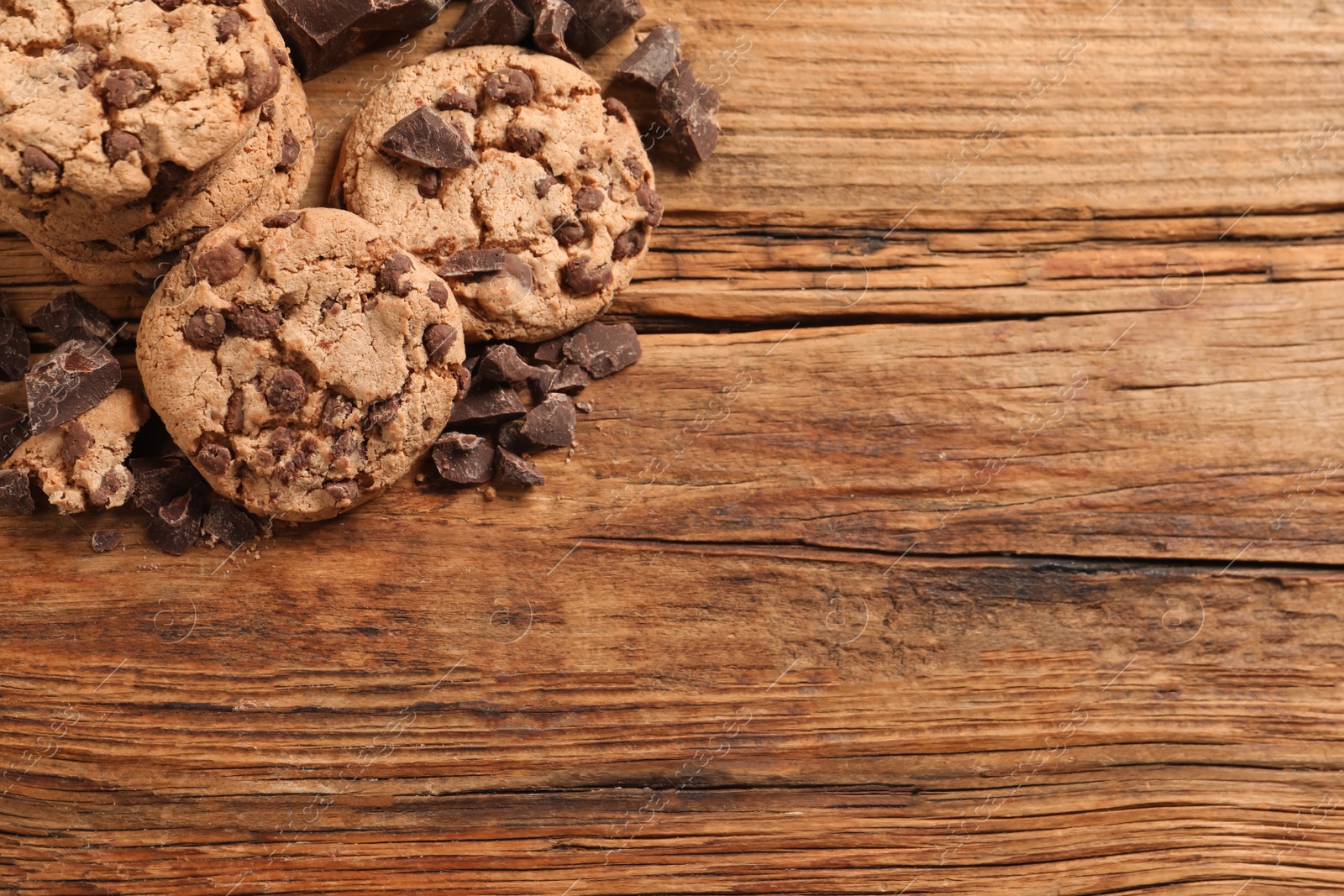 Photo of Many delicious chocolate chip cookies on wooden table, top view. Space for text