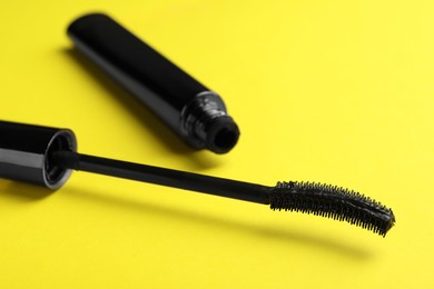 Mascara for eyelashes on yellow background, closeup. Makeup product