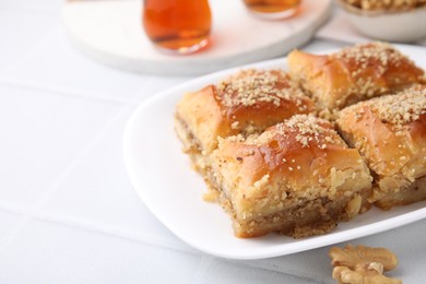 Photo of Eastern sweets. Pieces of tasty baklava and tea on white tiled table, closeup. Space for text