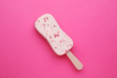 Photo of Delicious glazed ice cream bar on pink background, top view