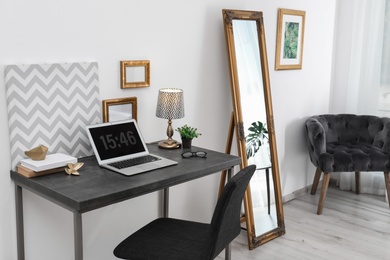 Photo of Stylish interior with modern laptop on table. Comfortable workplace