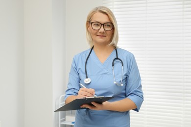 Photo of Doctor wearing uniform with clipboard in clinic