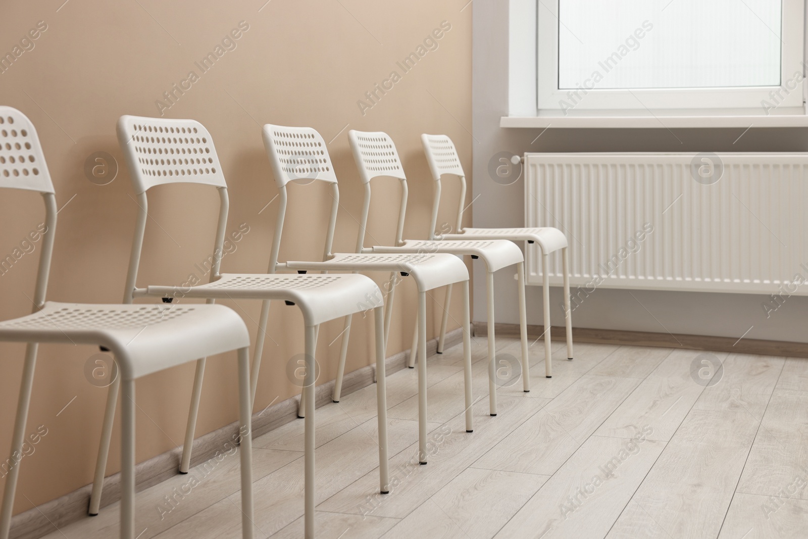 Photo of Many chairs near beige wall in waiting area indoors