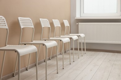 Many chairs near beige wall in waiting area indoors