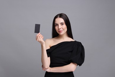 Woman holding blank business card on grey background