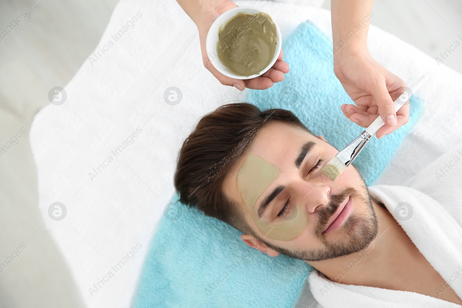 Photo of Cosmetologist applying mask on client's face in spa salon, above view