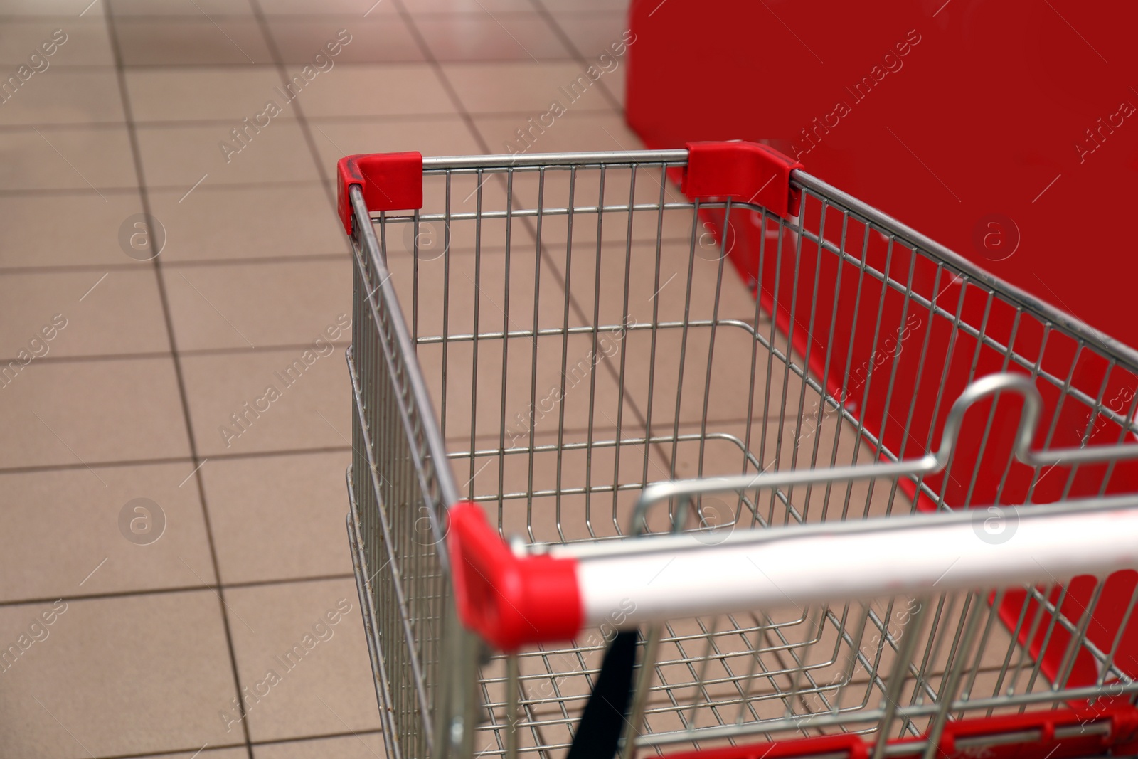 Photo of Empty metal shopping cart in supermarket, closeup