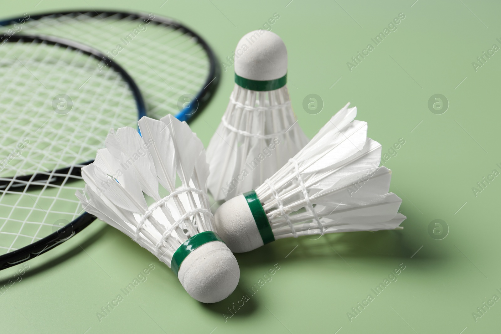 Photo of Feather badminton shuttlecocks and rackets on green background, closeup