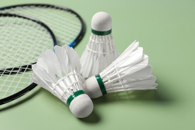Feather badminton shuttlecocks and rackets on green background, closeup