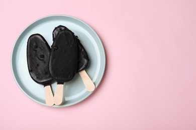 Photo of Plate with glazed ice cream bars on pink background, top view. Space for text