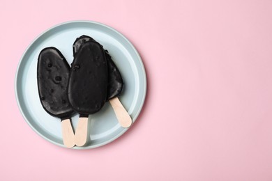 Plate with glazed ice cream bars on pink background, top view. Space for text