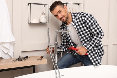 Photo of Man installing water tap with shower head in bathroom