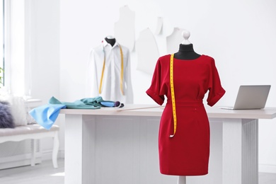 Photo of Mannequin with dress and measuring tape in tailor studio