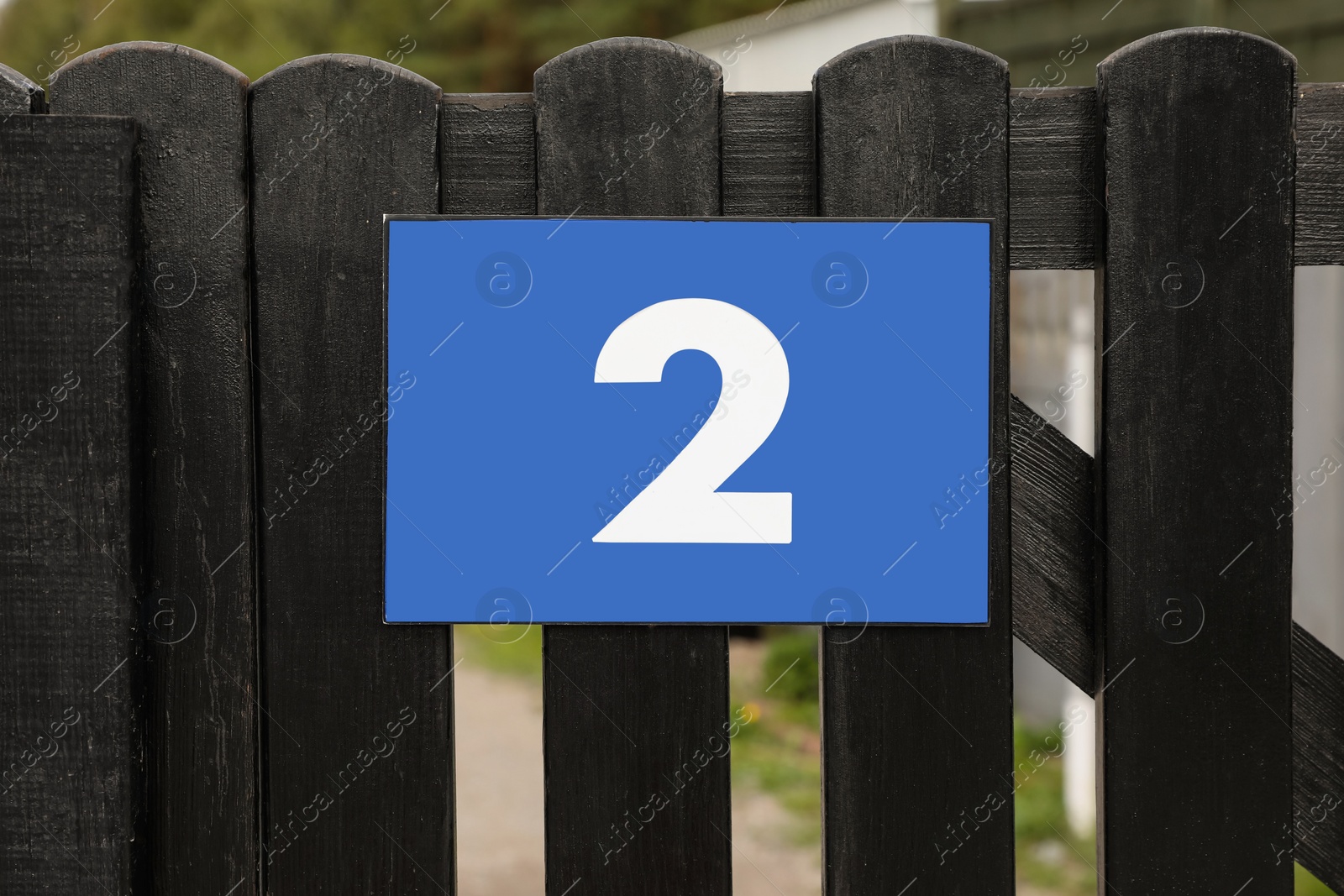 Photo of Plate with house number two on wooden fence outdoors, closeup