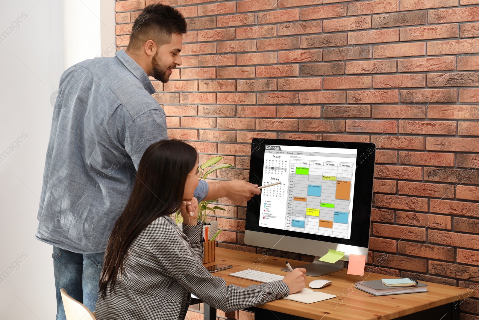 Photo of Colleagues working with calendar app on computer in office