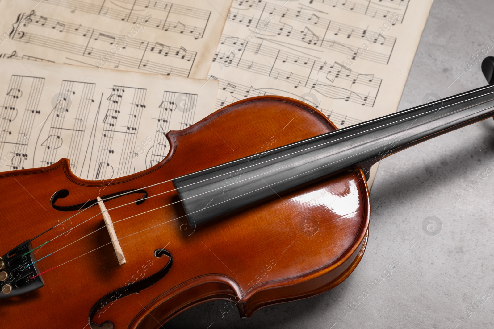 Photo of Violin and music sheets on grey table, closeup