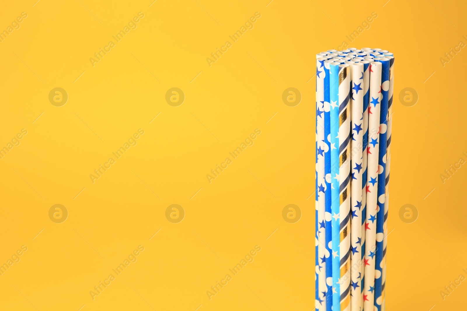 Photo of Colorful paper drinking straws on yellow background. Space for text