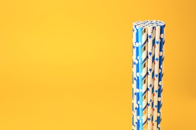 Photo of Colorful paper drinking straws on yellow background. Space for text