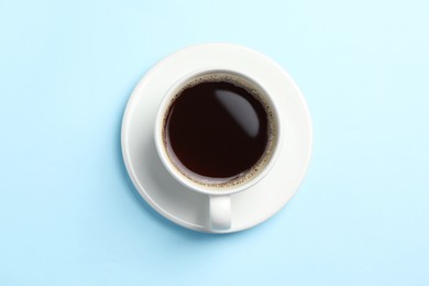 Cup of aromatic coffee on light blue background, top view