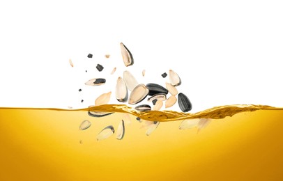 Image of Sunflower seeds falling into cooking oil on white background