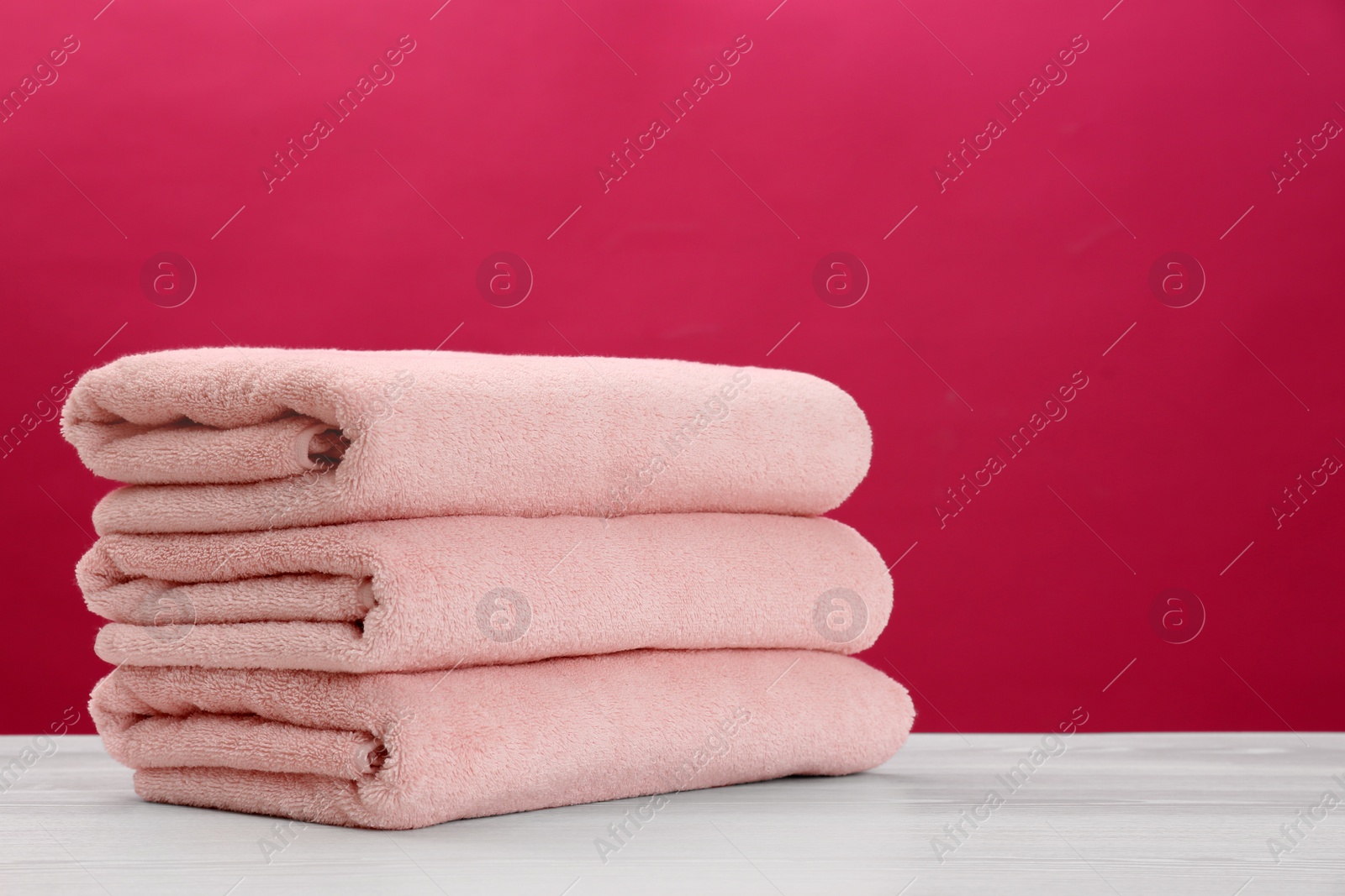 Photo of Stack of soft clean towels on table against color background. Space for text