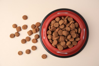 Dry dog food and feeding bowl on beige background, flat lay