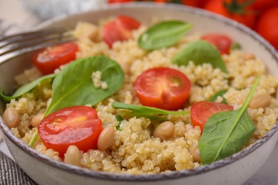Delicious quinoa salad with tomatoes, beans and spinach leaves, closeup