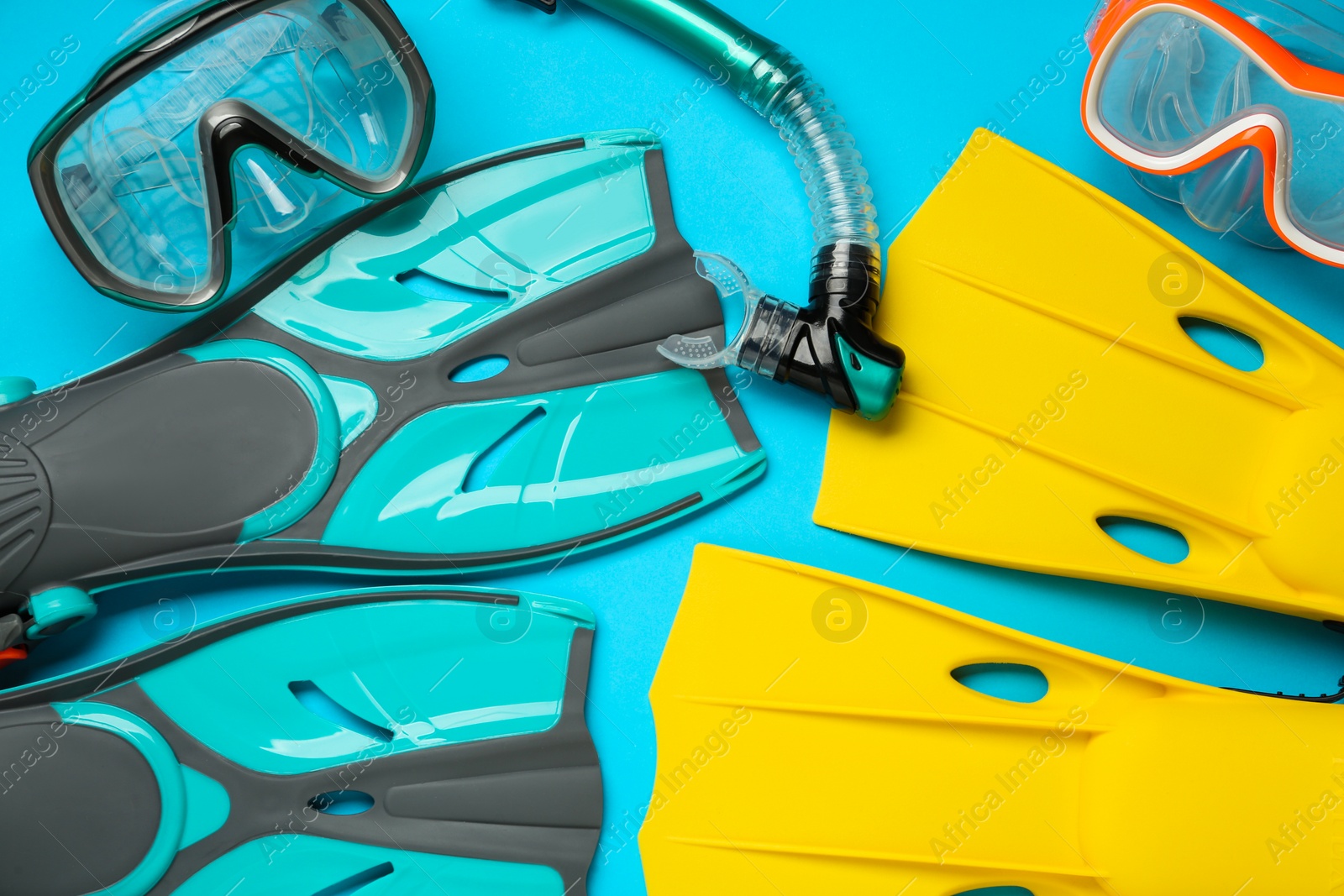 Photo of Different flippers and mask on light blue background, flat lay