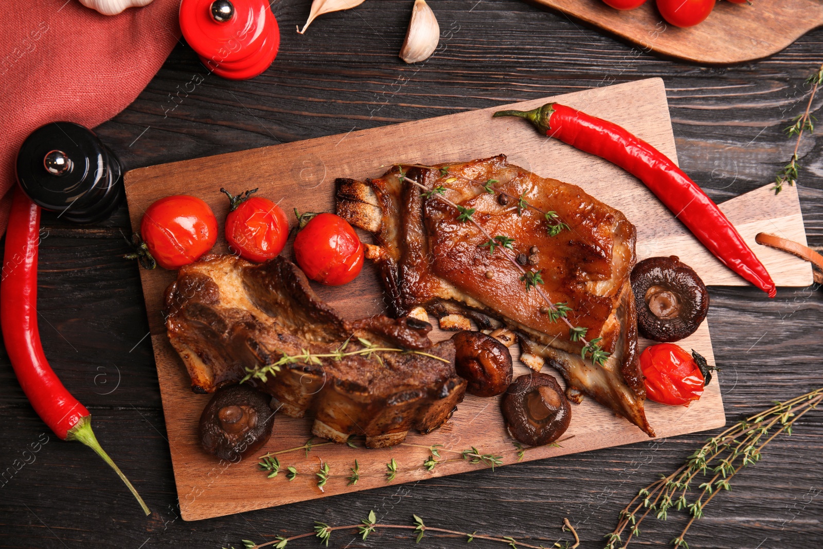 Photo of Delicious roasted ribs served on black wooden table, flat lay