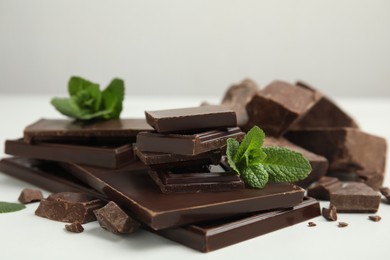 Photo of Tasty dark chocolate pieces with mint on white table