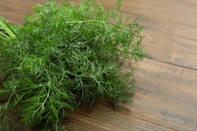 Photo of Fresh green dill on wooden table, closeup. Space for text