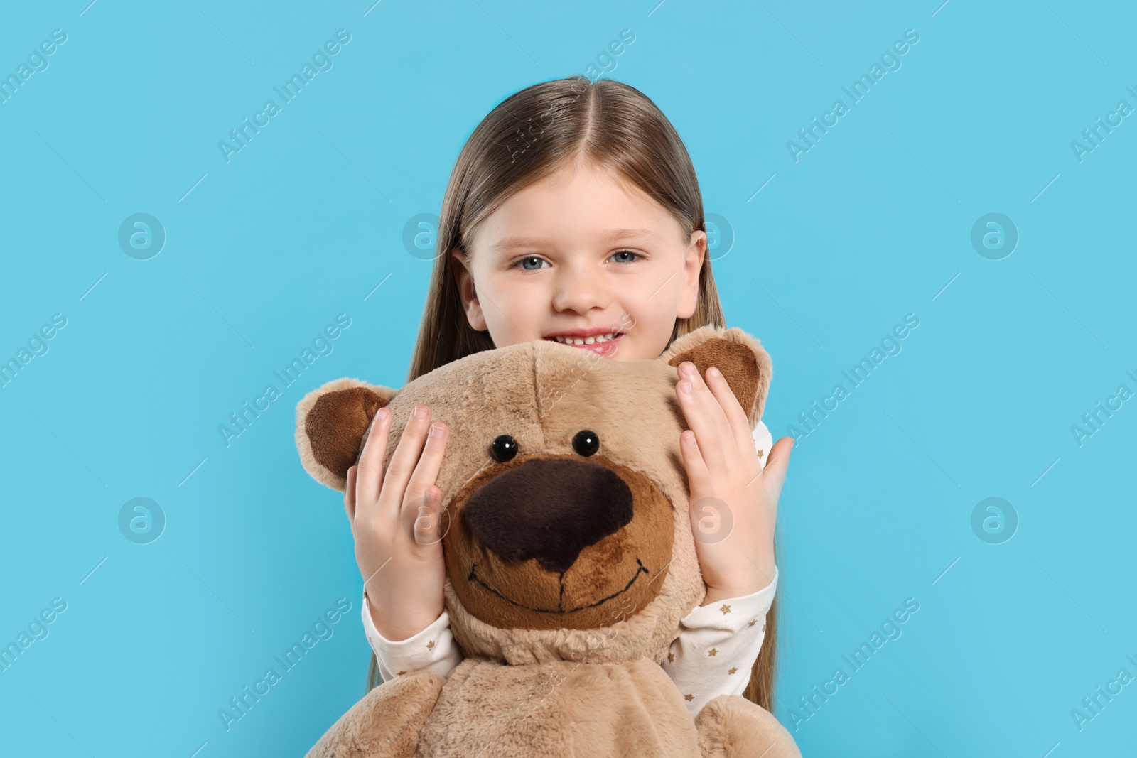 Photo of Cute little girl with teddy bear on light blue background