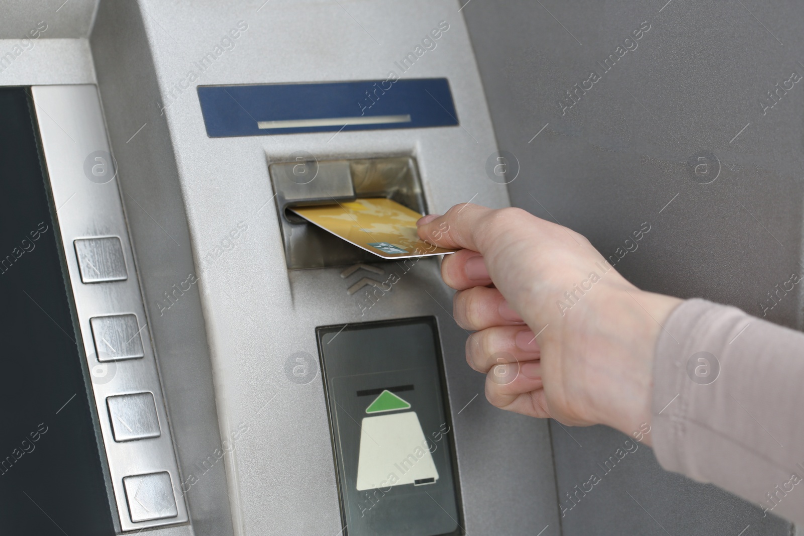 Photo of Woman inserting credit card into grey cash machine, closeup