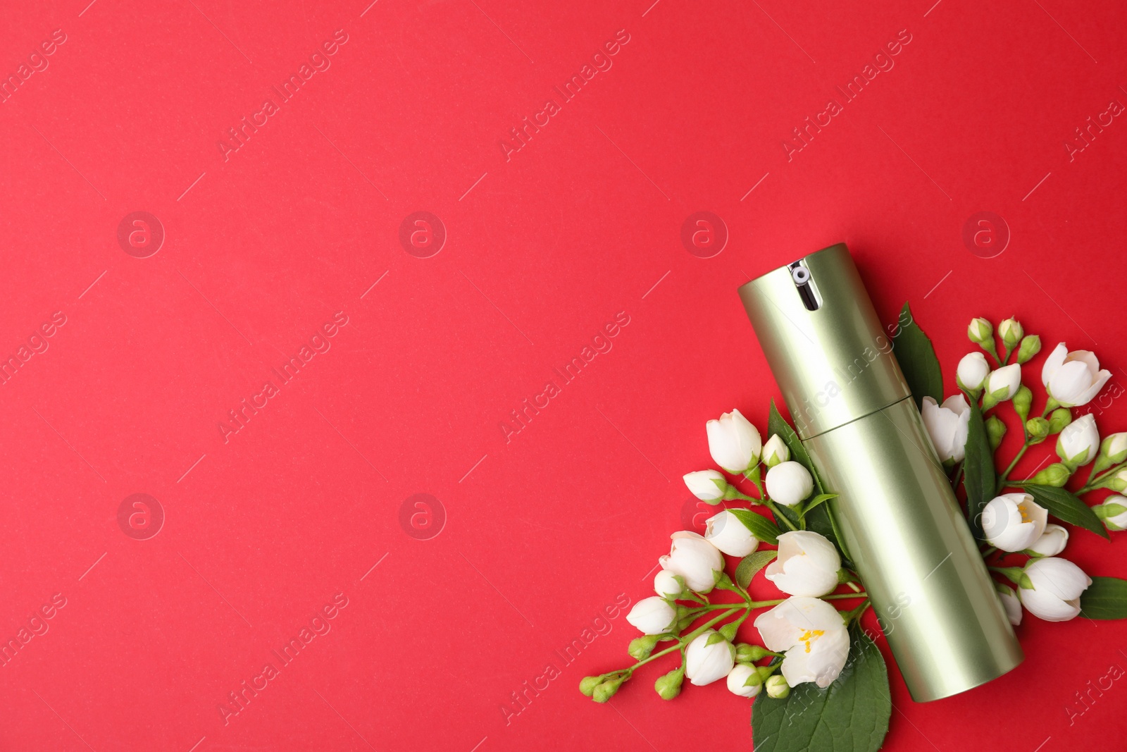 Photo of Bottle of cosmetic product and flowers on red background, flat lay. Space for text