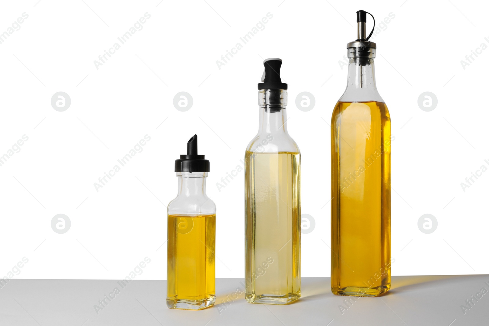 Photo of Bottles of different cooking oils on white background