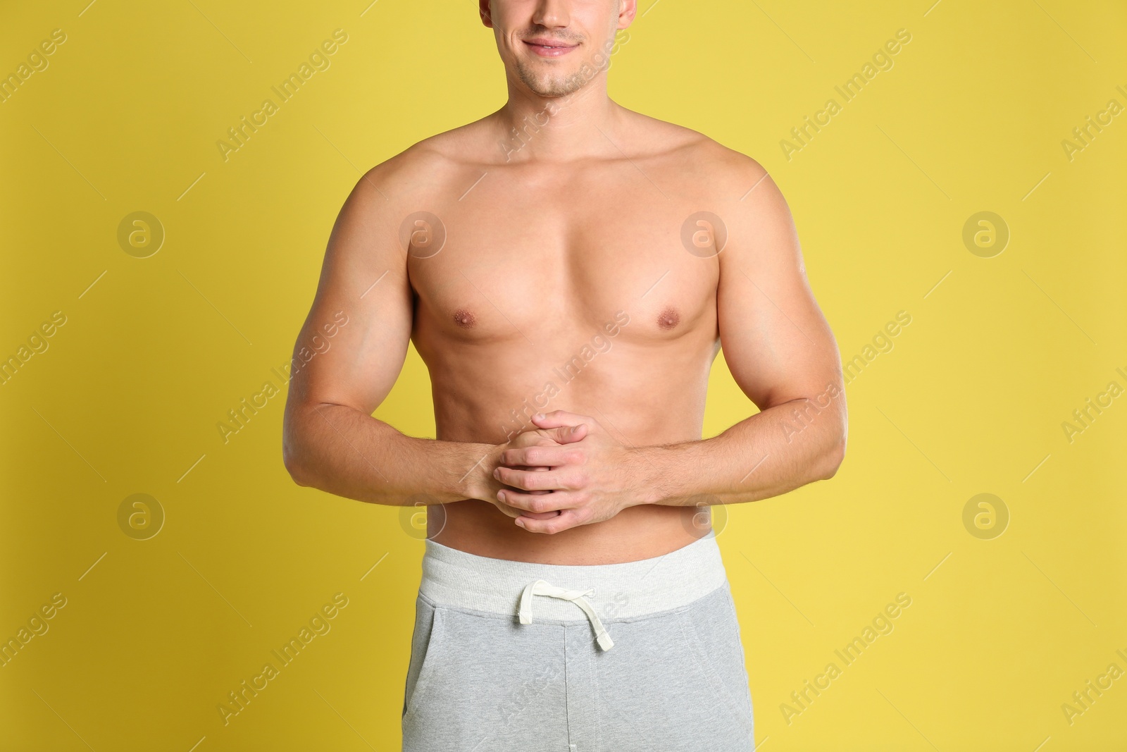 Photo of Man with sexy body on yellow background, closeup