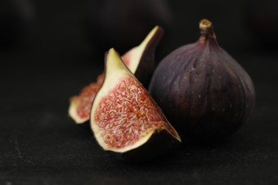 Photo of Tasty raw figs on black slate table, closeup