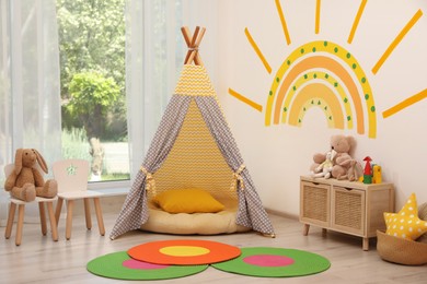 Photo of Cute child's room interior with beautiful sun painted on wall