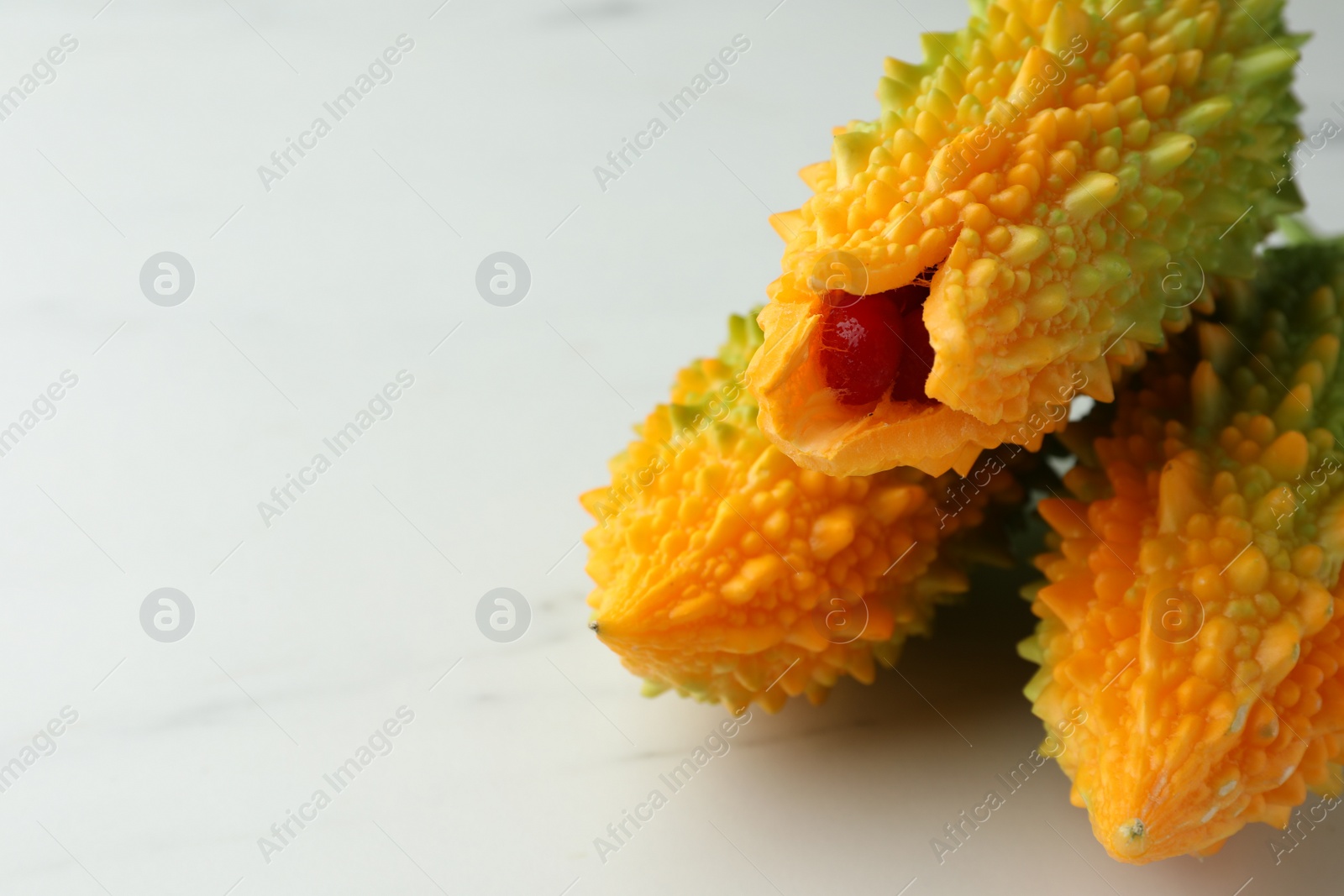 Photo of Bitter melons on white marble table, closeup. Space for text