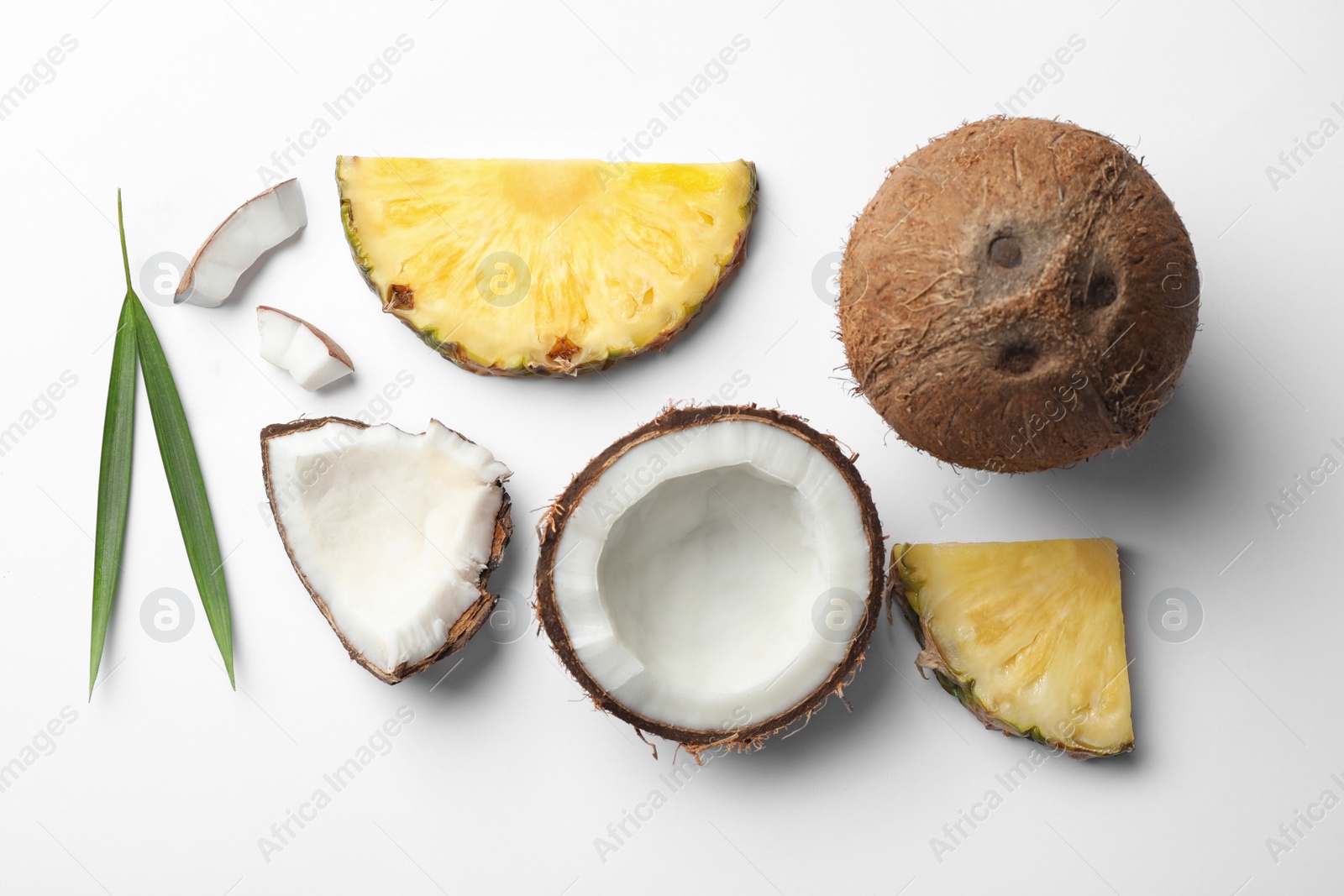 Photo of Composition with coconuts, juicy and leaves pineapple slices on white background, top view