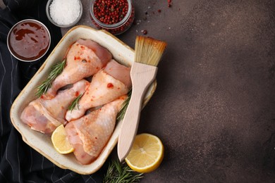 Photo of Flat lay composition with marinade and raw chicken drumsticks on brown table. Space for text