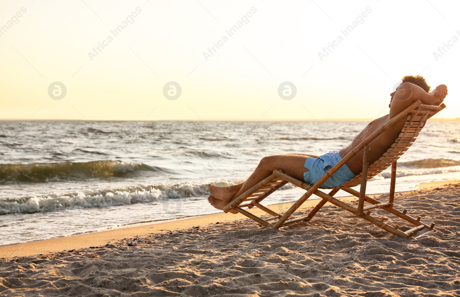 Photo of Young man relaxing in deck chair on beach near sea