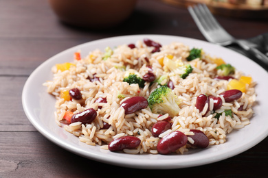 Photo of Delicious rice with beans served on wooden table, closeup