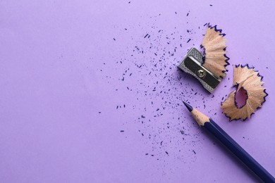 Photo of Blue pencil, shavings, crumbs and sharpener on violet background, flat lay. Space for text