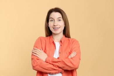 Portrait of smiling woman with dental braces on beige background