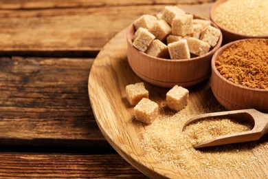 Photo of Plate with different types of sugar on wooden table, space for text