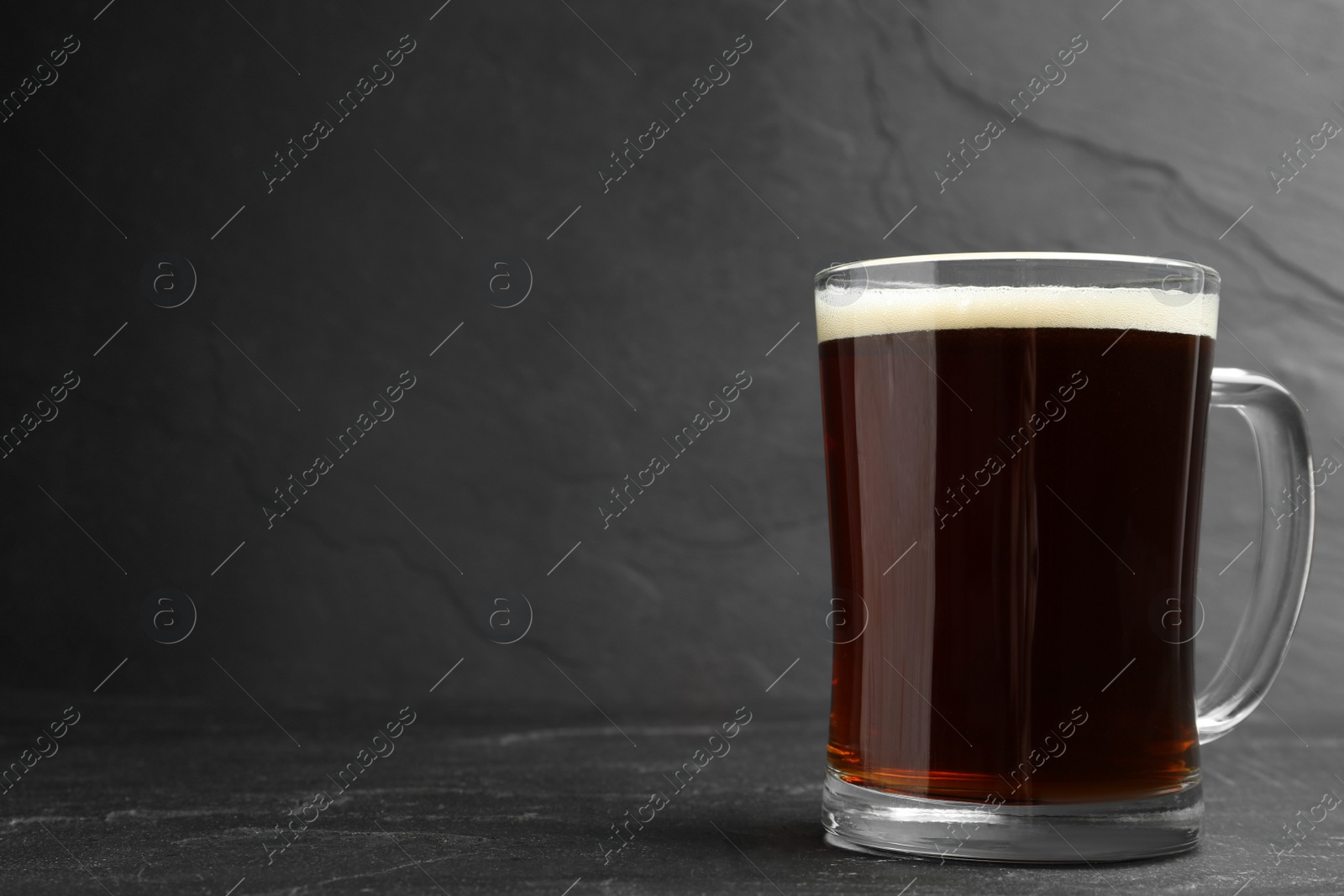 Photo of Mug of delicious kvass in mug on black table. Space for text
