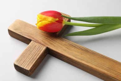 Easter - celebration of Jesus resurrection. Wooden cross and tulip on light background, closeup