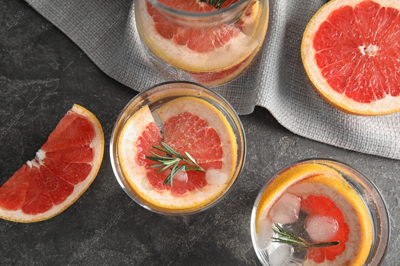 Photo of Glasses of infused water with grapefruit slices on grey table, flat lay