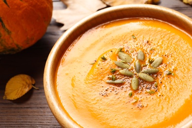 Photo of Bowl with tasty pumpkin soup on wooden table